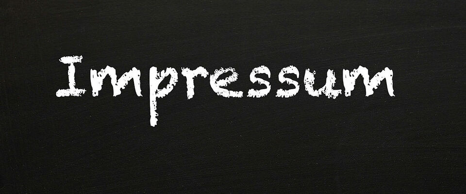 Das Wort "Impressum" mit weißer Kreide auf schwarzer Tafel geschrieben